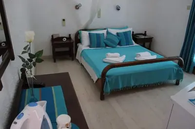 a bedroom with a blue bed with blue pillows at Artemis Rooms in Agia Marina Aegina