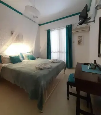 a bedroom with a bed with a desk and a window at Artemis Rooms in Agia Marina Aegina