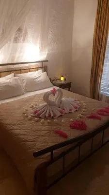 a bed with a dress on it with flowers on it at Artemis Rooms in Agia Marina Aegina