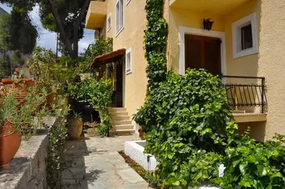 a house with green plants in front of it at Artemis Rooms in Agia Marina Aegina