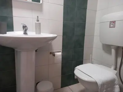 a bathroom with a white toilet and a sink at Helen's Welcoming & cozy flat in Koropíon