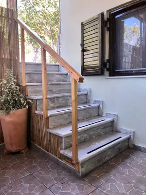 a wooden staircase next to a window with a potted plant at Helen's Welcoming & cozy flat in Koropíon