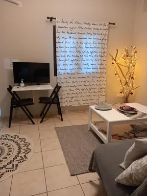 a living room with a table and a television at Helen's Welcoming & cozy flat in Koropíon