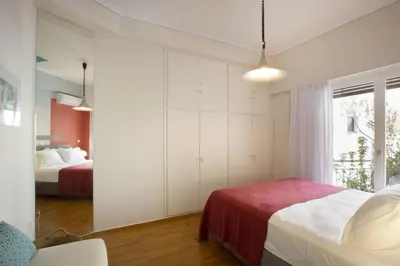 a white bedroom with two beds and a window at Little gem 2 mins from Acropolis Museum in Athens
