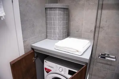 a bathroom with a washing machine under a counter at Katia Modern Apartment in Athens in Athens