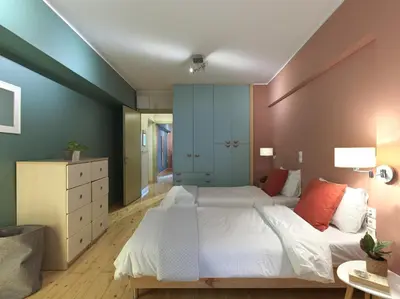 a bedroom with a large bed with white sheets and orange pillows at Koukaki garden escape child friendly apartment in Athens