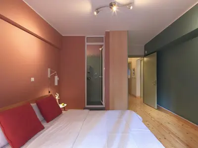 a bedroom with a large white bed with red pillows at Koukaki garden escape child friendly apartment in Athens