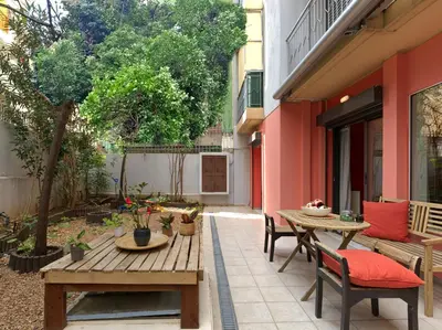 an outdoor patio with a wooden table and chairs at Koukaki garden escape child friendly apartment in Athens