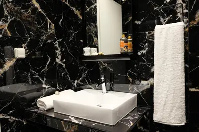 a bathroom with a white sink and black marble walls at STUDIO ANASTASIA in Athens