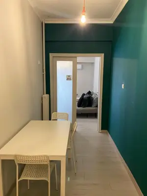 a table and chairs in a room with a green wall at Aris Apartment in Athens