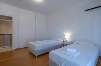 two beds in a white room with a room with a window at Hippocrates - Faliro deluxe apartment in Athens