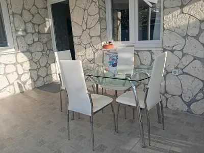 a glass table and white chairs on a patio at Antonia family house near Airport in Porto Rafti