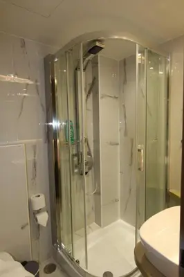 a glass shower in a bathroom with a sink at Aiolos Apartments Ermou 64 Monastiraki, Plaka 4th floor in Athens