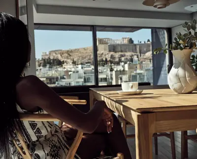 a woman sitting at a table looking out a window at Urban Stripes Athens in Athens