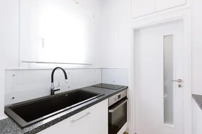 a white kitchen with a sink and a stove at Minimal apartment on the shadow of the Acropolis in Athens