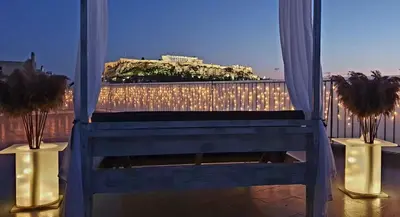 a blue chair sitting on a balcony with lights at Acropolis View Apartment in the Heart of Monastiraki in Athens
