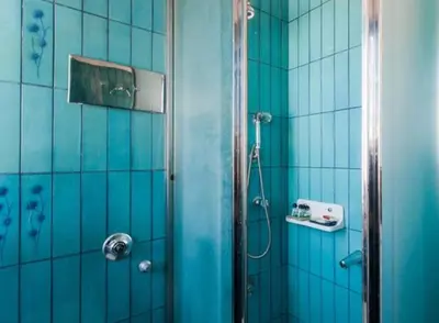 a bathroom with a shower with blue tiled walls at Luxury Athenian Riviera Apartment 135 sqm at Voula in Athens