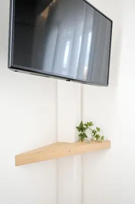 a tv hanging on a wall with a wooden shelf at Odyssey Residence in Athens