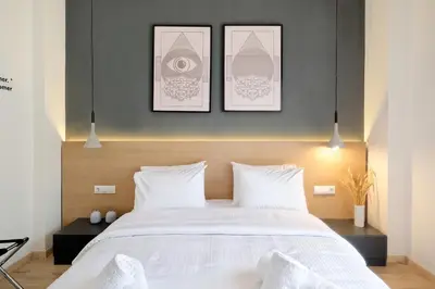 a bedroom with a white bed with three pictures on the wall at Odyssey Residence in Athens