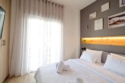 a bedroom with a white bed with a large window at Odyssey Residence in Athens