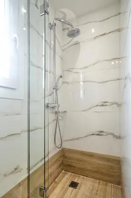 a shower in a bathroom with white marble walls at Odyssey Residence in Athens