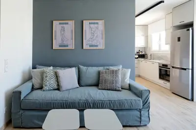 a blue couch in a living room with a kitchen at Odyssey Residence in Athens