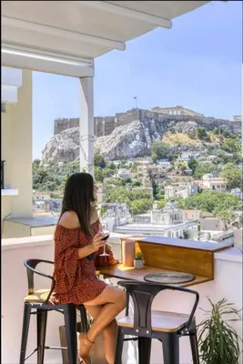 a woman sitting at a table with a view ofhens at Acropolis stunning view Penthouse in Plaka for 2! in Athens