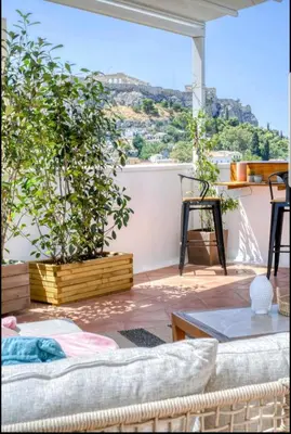 a living room with a large window with plants at Acropolis stunning view Penthouse in Plaka for 2! in Athens