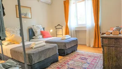 a bedroom with two beds and a ottoman at A Happy Stay at Edem Beach by Athenian Homes in Athens