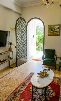 a living room with a table and a chair and a door at A Happy Stay at Edem Beach by Athenian Homes in Athens