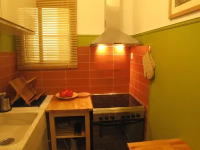 a kitchen with a stove and a bowl of fruit on a table at Homey and calm yet central (by the Hilton) in Athens