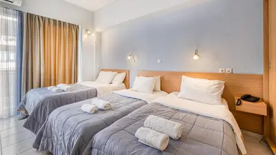 a hotel room with three beds with towels on them at Diros Hotel in Athens