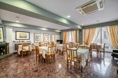 a restaurant with tables and chairs and a piano at Diros Hotel in Athens