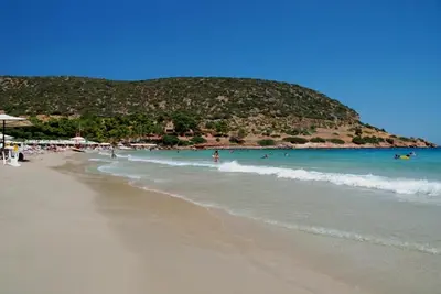 a beach with people in the water and a hill at Vaso's country house near the beach and airport in Porto Rafti