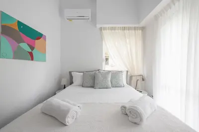 a white bedroom with a bed with towels on it at Garden Villa Glyfada in Athens