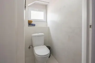 a white bathroom with a toilet and a window at Garden Villa Glyfada in Athens