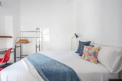 a white bed with pillows and a red chair at Garden Villa Glyfada in Athens