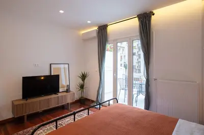 a bedroom with a bed and a television and a balcony at Phaedrus Living: City Centre Luxury Flat Mavromichali in Athens