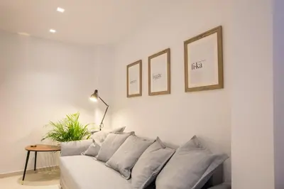 a living room with a white couch with three pictures on the wall at Phaedrus Living: City Centre Luxury Flat Mavromichali in Athens