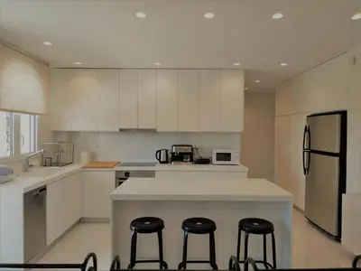 a kitchen with white cabinets and a counter with stools at Luxury Garden Apartment Glyfada in Athens