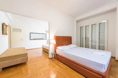 a white bedroom with a bed and a table at Victoria Plaza Palace Apartments in Athens
