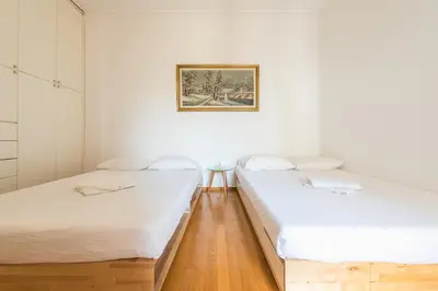 two beds in a room with white walls and wooden floors at Victoria Plaza Palace Apartments in Athens