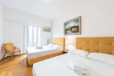 a hotel room with two beds and a chair at Victoria Plaza Palace Apartments in Athens