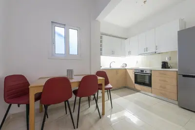 a kitchen with a wooden table and red chairs at Victoria Queens Suites Apartments in Athens