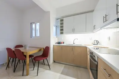 a kitchen with a wooden table and red chairs at Victoria Queens Suites Apartments in Athens