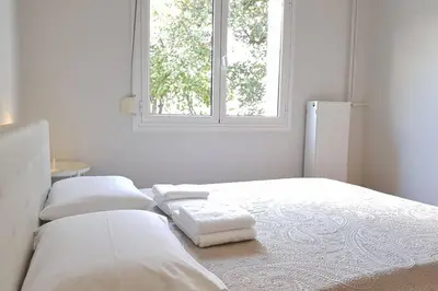 a white bedroom with two beds and a window at A Great Stay at a Comfortable Large Apartment in Athens