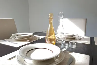 a table with white plates and a bottle on it at A Great Stay at a Comfortable Large Apartment in Athens