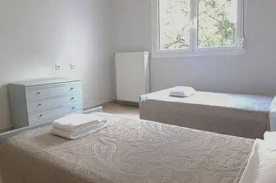 a bedroom with two beds and a dresser and two windows at A Great Stay at a Comfortable Large Apartment in Athens