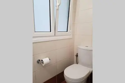a bathroom with a toilet and a window at A Great Stay at a Comfortable Large Apartment in Athens