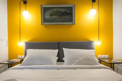 a bedroom with yellow walls and a bed with white pillows at Vol.3 in Athens